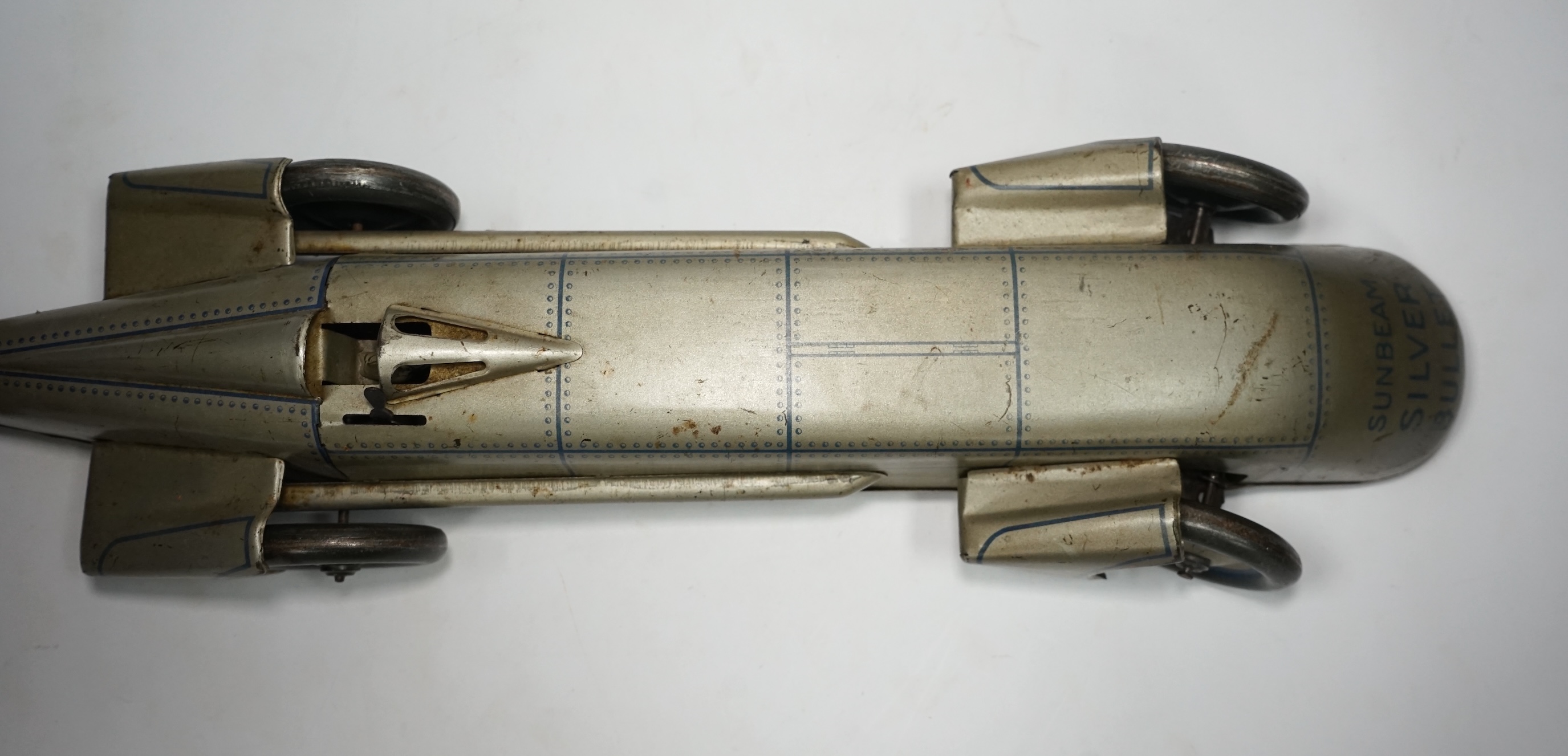 A 1930s Gunthermann (Germany) clockwork tinplate Sunbeam Silver Bullet world record car, with blue printed panel and rivet detail, driver, and Union flags to tail fins, stamped with ‘Foreign’ to underside, 56cm long. Con